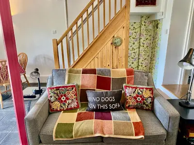 a couch with two pillows and a no dog on this sofa at Frogmore Corner in Tregoney