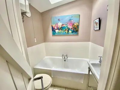 a bathroom with a white tub and a painting on the wall at Frogmore Corner in Tregoney