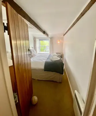a small bedroom with a bed and a window at Frogmore Corner in Tregoney