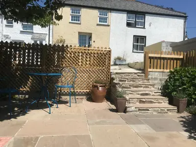 a patio with a table and chairs in front of a house at Frogmore Corner in Tregoney