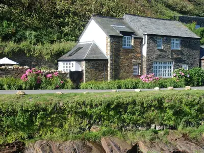 a stone house with flowers in front of it at The Old Store House in Boscastle