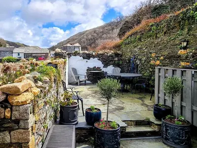 a patio with potted plants and a stone wall at The Old Store House in Boscastle