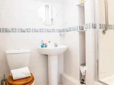 a bathroom with a sink and a toilet and a mirror at The Old Store House in Boscastle