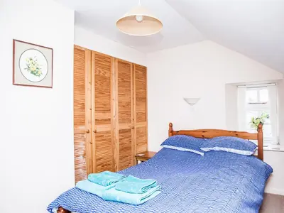 a bedroom with a blue bed with a wooden headboard at The Old Store House in Boscastle