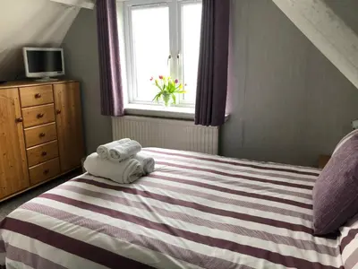 a bedroom with a striped bed with towels on it at Borthalan House in Carbis Bay