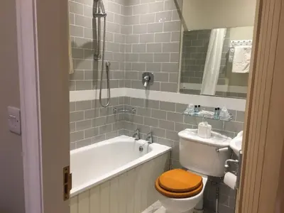 a bathroom with a toilet and a tub and a sink at The Galleon Inn in Fowey