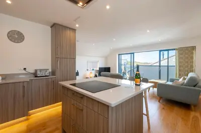 a kitchen with a counter and a living room at Sandpiper Cottages in Newquay