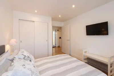 a bedroom with a bed and a tv on the wall at Sandpiper Cottages in Newquay