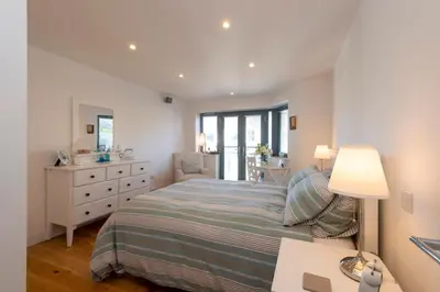 a bedroom with a bed and a desk with a lamp at Sandpiper Cottages in Newquay