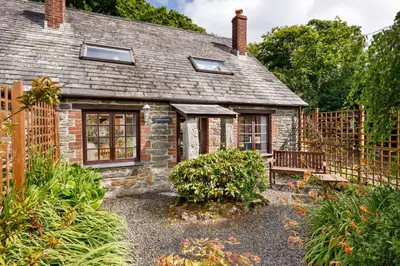 an old stone cottage with a bench in front of it at Little Leighs in Launceston