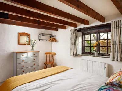 a bedroom with a bed and a dresser and a window at Beech Cottage in Launceston