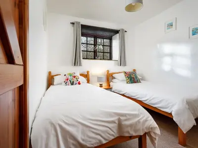 two beds in a room with white walls and a window at Beech Cottage in Launceston
