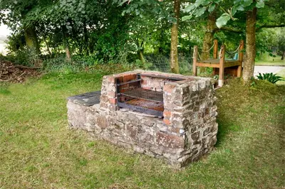 a brick oven in the grass next to a bench at Beech Cottage in Launceston