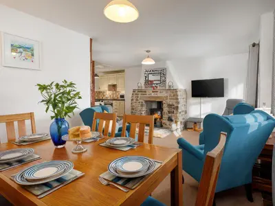 a dining room with a wooden table and blue chairs at Beech Cottage in Launceston