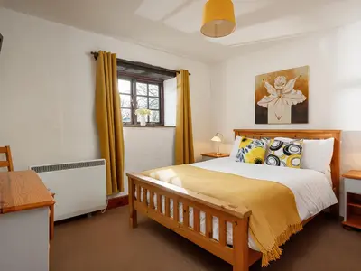 a bedroom with a large bed with yellow curtains at Ash Cottage in Launceston