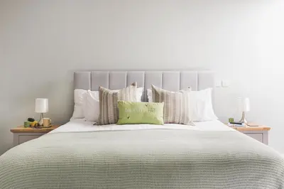 a large bed with white pillows and a green pillow at Ocean-Walk Granny's Lane Perranporth in Perranporth