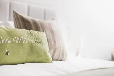 a green pillow sitting on top of a bed at Ocean-Walk Granny's Lane Perranporth in Perranporth