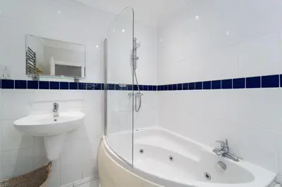 a white bathroom with a sink and a tub and a sink at Sea Shells in St Ives
