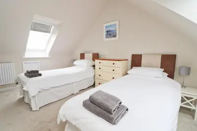 a bedroom with two beds and a window at BY THE BEACH cottage, dogs welcome in St Merryn