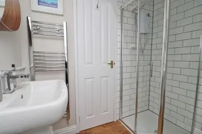 a white bathroom with a sink and a shower at BY THE BEACH cottage, dogs welcome in St Merryn