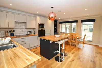 a kitchen with white cabinets and a wooden counter top at BY THE BEACH cottage, dogs welcome in St Merryn