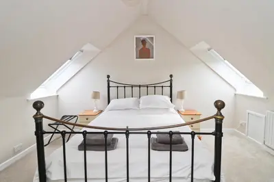 a bedroom with a black bed in a attic at BY THE BEACH cottage, dogs welcome in St Merryn