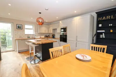 a kitchen and dining room with a wooden table at BY THE BEACH cottage, dogs welcome in St Merryn