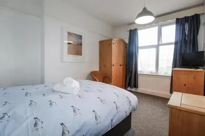 a bedroom with a bed and a tv and a window at The Three Tees in Newquay