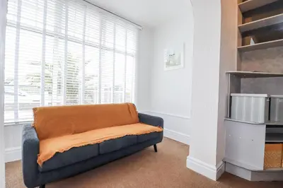 a living room with a couch with an orange blanket at The Three Tees in Newquay