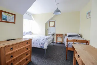 a bedroom with a bed and a dresser and a desk at The Three Tees in Newquay