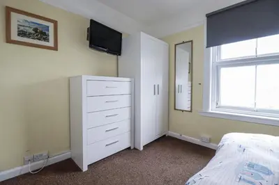 a bedroom with a white dresser and a tv on the wall at The Three Tees in Newquay