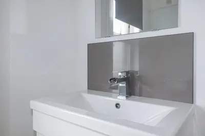 a white bathroom sink with a mirror above it at The Three Tees in Newquay