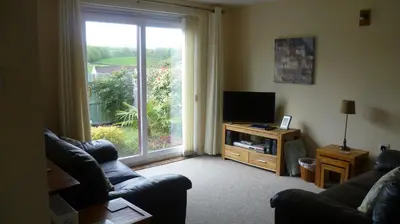 a living room with a large window and a television at Sunny detached bungalow, Nr Looe in Saint Keyne