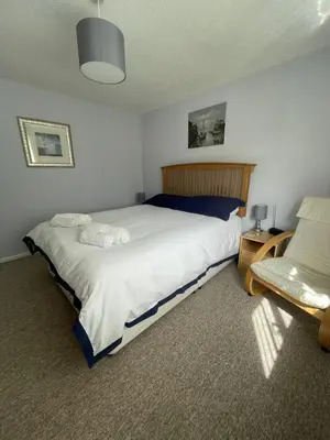 a bedroom with a large bed and a chair at Sunny detached bungalow, Nr Looe in Saint Keyne