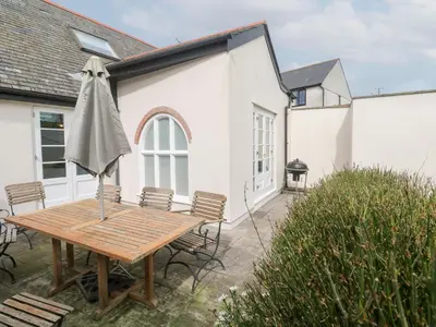 a patio with a wooden table and an umbrella at No 3 The Hinges in Newquay