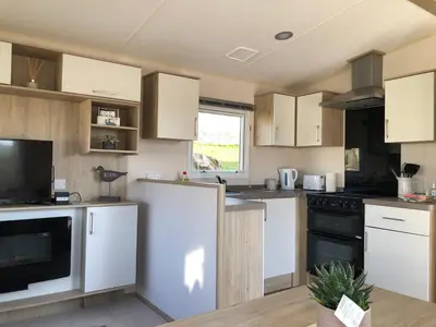 a kitchen with white cabinets and a black appliance at Newquay Bay Resort - SummerBreeze PV54 in Porth