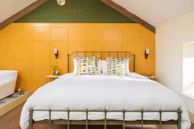 a bedroom with a large bed and a yellow wall at The Duchy Barn at Tregoose Old Mill in Newquay