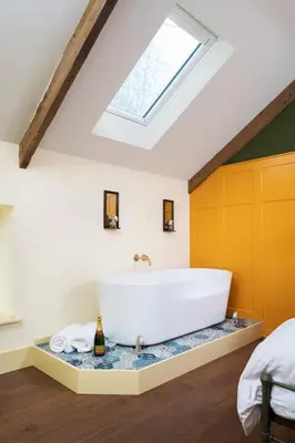 a bathroom with a large white tub in a attic at The Duchy Barn at Tregoose Old Mill in Newquay