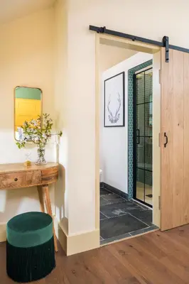 a door leading into a room with a green ottoman at The Duchy Barn at Tregoose Old Mill in Newquay