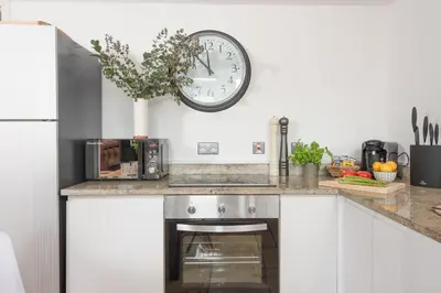 a kitchen with a clock on the wall above a stove at Mr Blue Sky in St Ives