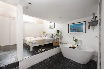 a bathroom with a tub and a bed in a room at Mr Blue Sky in St Ives