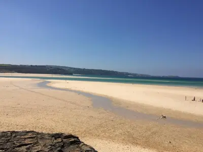 a beach with a group of people and the ocean at Bodriggy Barn Holiday Cottage near St Ives in Hayle