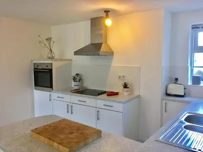 a white kitchen with a sink and a microwave at Bodriggy Barn Holiday Cottage near St Ives in Hayle