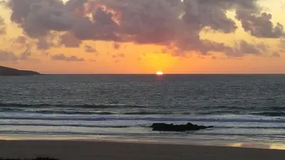 a sunset over the ocean with the sun in the distance at Bodriggy Barn Holiday Cottage near St Ives in Hayle