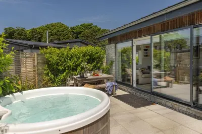a bath tub on a patio with a house at 6 The Dunes At Upton Towans - Short walk to the beach - Hot Tub - Free Wi-Fi in Hayle