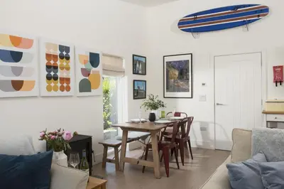 a dining room with a table and chairs and a surfboard on the wall at 6 The Dunes At Upton Towans - Short walk to the beach - Hot Tub - Free Wi-Fi in Hayle