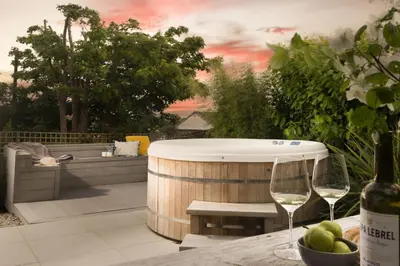 a hot tub and two wine glasses on a table at 6 The Dunes At Upton Towans - Short walk to the beach - Hot Tub - Free Wi-Fi in Hayle