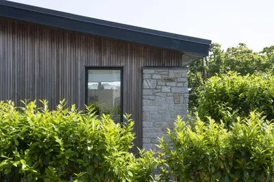 a small house with a window and some bushes at 6 The Dunes At Upton Towans - Short walk to the beach - Hot Tub - Free Wi-Fi in Hayle