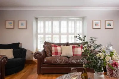 a living room with a brown leather couch and a window at 3 The Manor - Opposite a golf course - Pet friendly - Wi-Fi in Uny Lelant