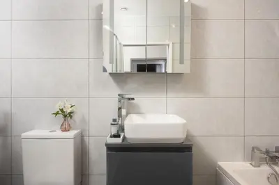 a bathroom with a sink and a toilet and a mirror at 3 The Manor - Opposite a golf course - Pet friendly - Wi-Fi in Uny Lelant